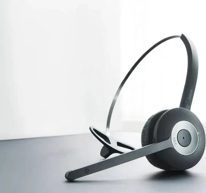 Jabra headset placed on a desk next to a laptop, highlighting devices compatible with the Now Reach system.