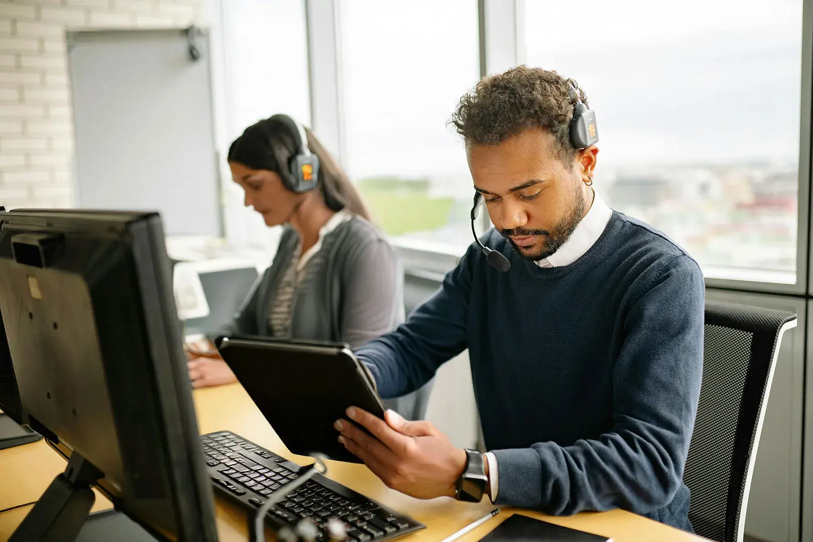 Customer support representatives using headsets and digital devices, providing answers to FAQs about the Now Reach System.