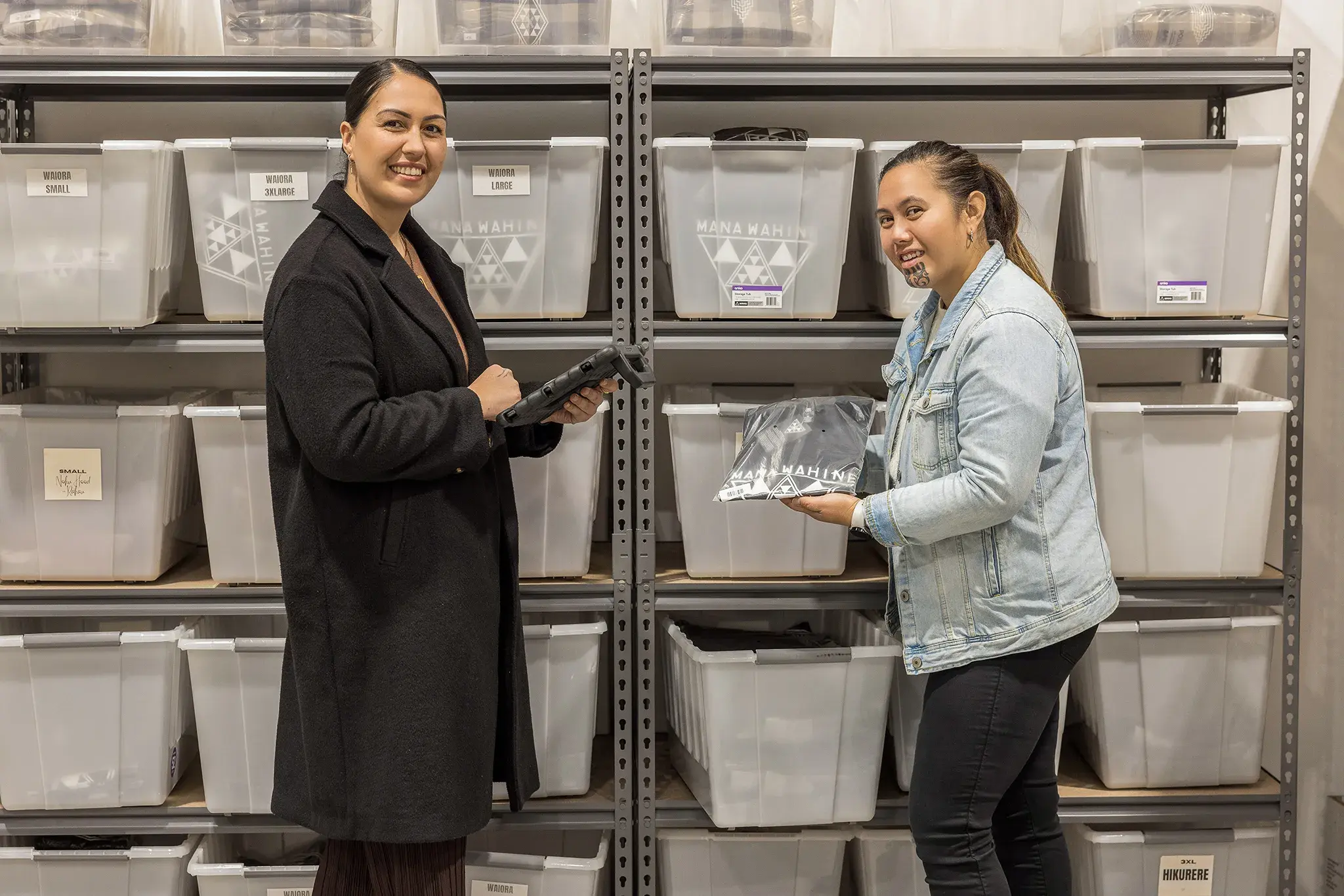 Two women standing in front of shelves filled with labeled storage bins. Tailored telco solutions focused on enabling Pakihi Māori to succeed. Empowering the future of Māori business.