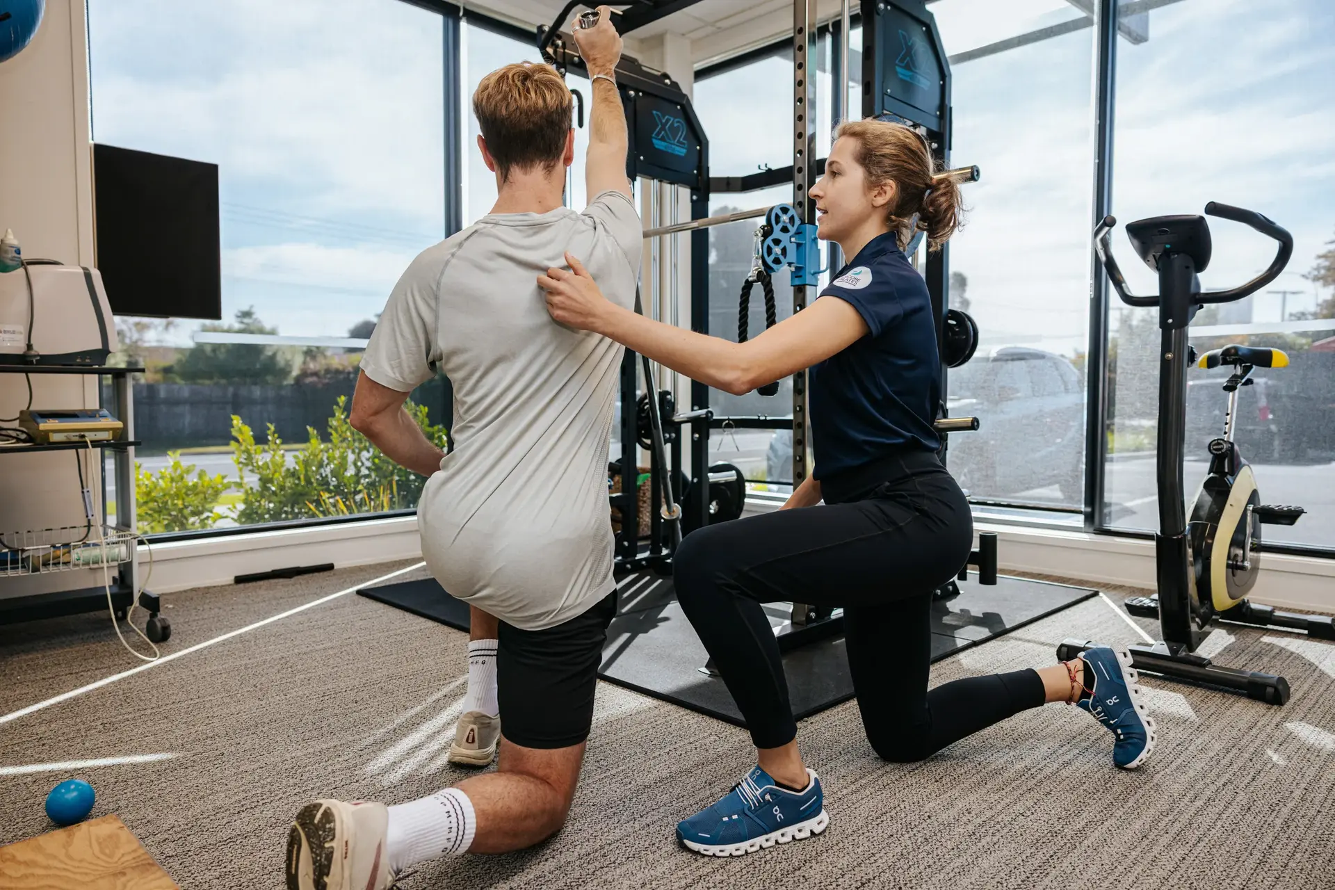 A Body in Motion therapist guides a client through a rehabilitation exercise in a well-lit clinic, showcasing the hands-on care made possible by reliable business broadband and phone solutions from Now.