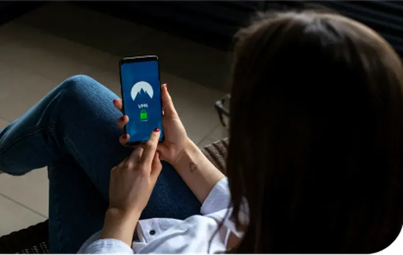 Woman using a smartphone with a VPN app activated, representing Now NZ's secure telco solutions for protecting patient information in the health and wellness industry.