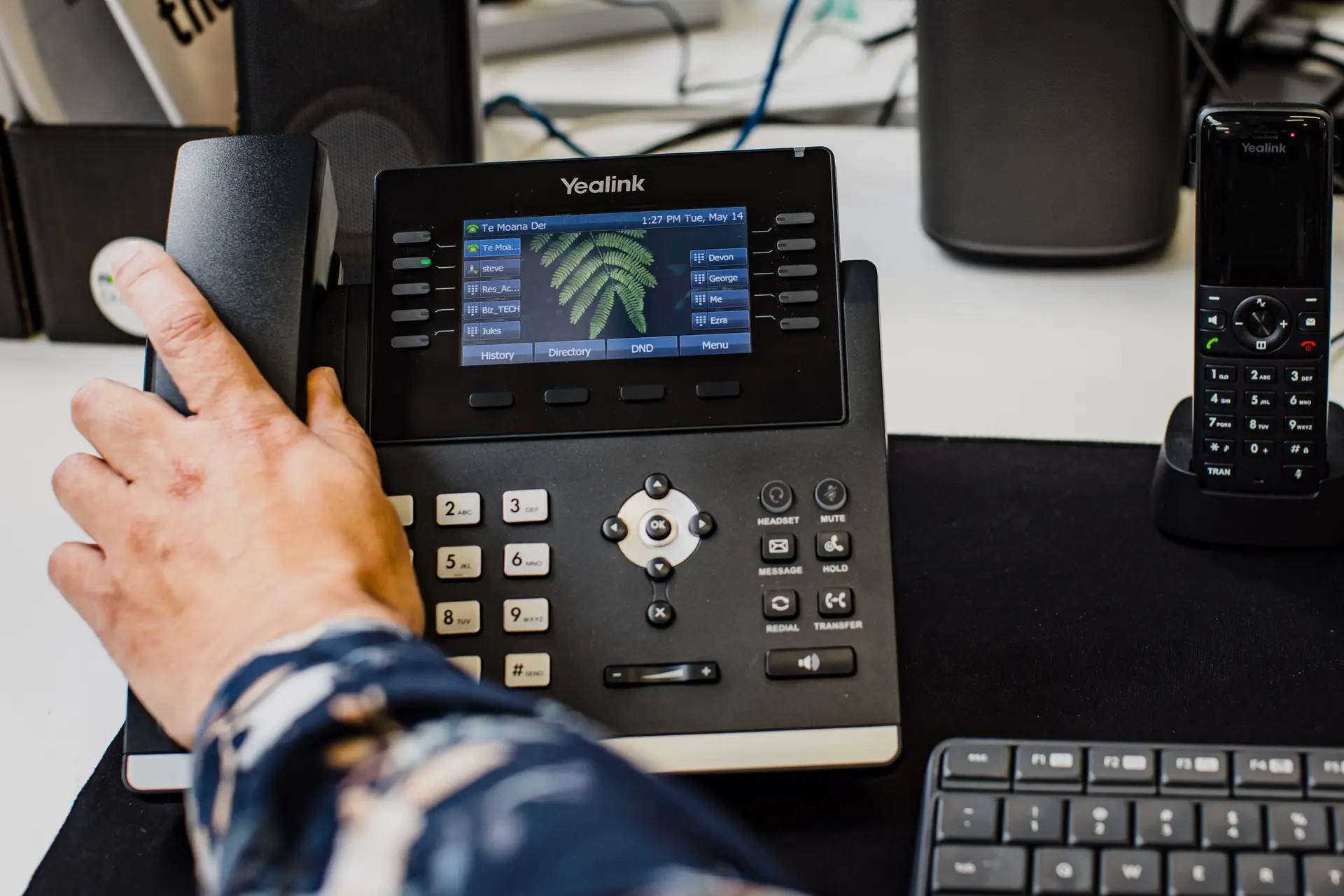 Hand using a Yealink desk phone, part of Now's smarter phone system, Now Reach, designed for flexible and efficient business communication.