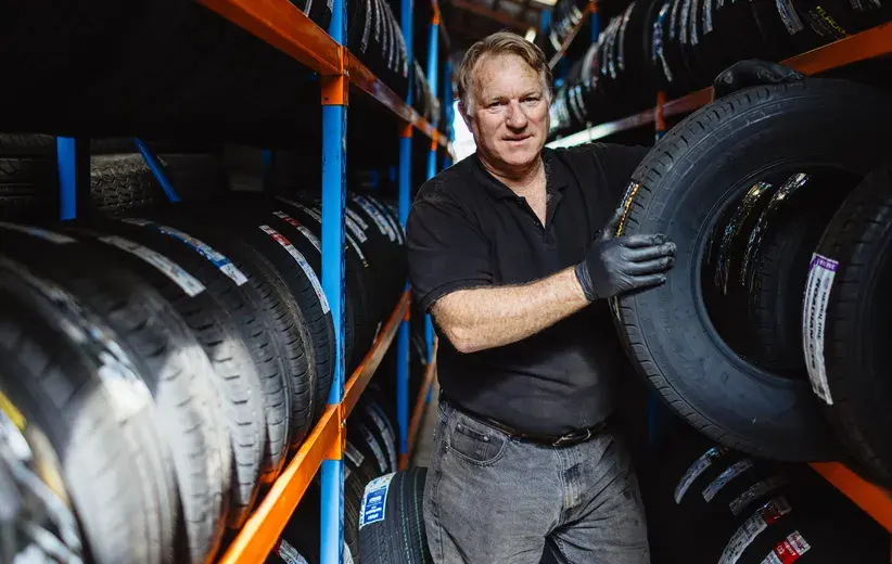 Tire shop worker organising inventory, illustrating Now NZ's award-winning service tailored for retail and trades businesses, providing essential speed, simplicity, and support.