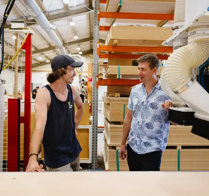 Two men talking in a woodworking shop, illustrating the benefits of internet-powered phone calls for businesses with on-site physical phone systems