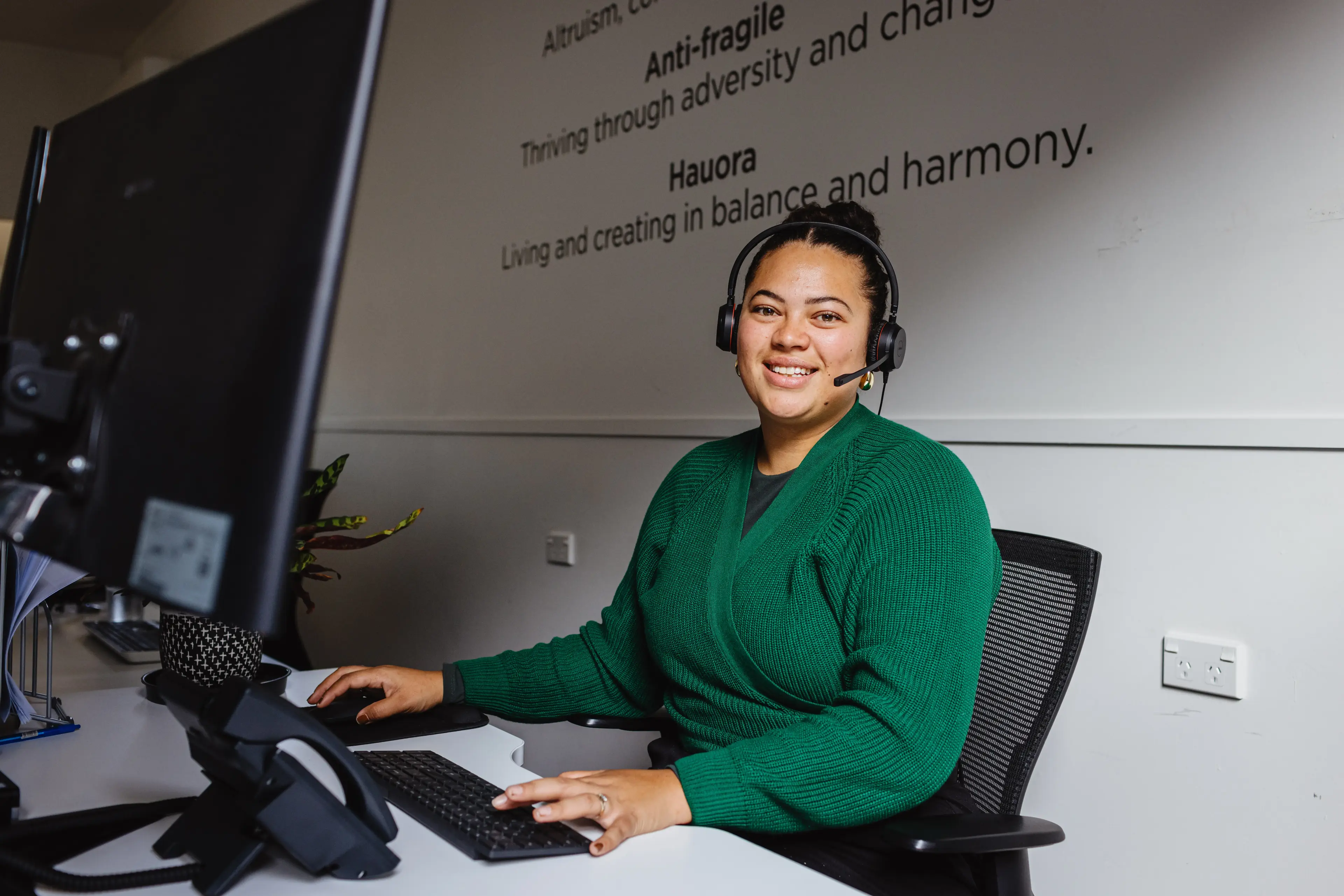 Support representative wearing a headset, ready to assist with mastering the Now Reach phone system through detailed tutorials.