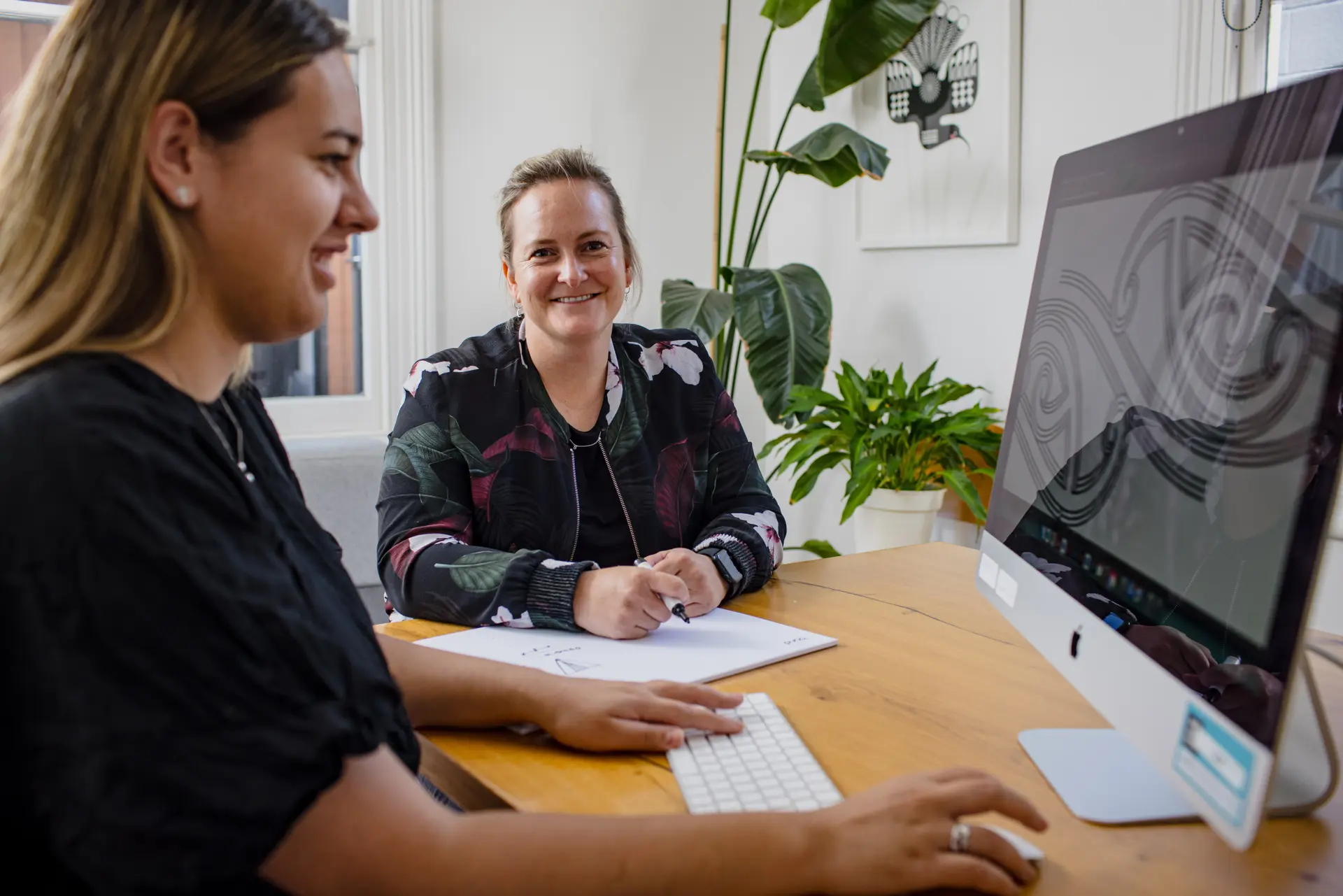 Two business professionals discussing telecommunications solutions at a desk, highlighting the importance of reliable connectivity for Kiwi businesses.