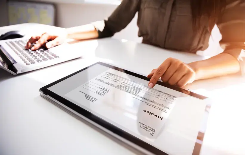 A person managing an invoice on a tablet while using a keyboard, illustrating Now NZ's account and billing services.