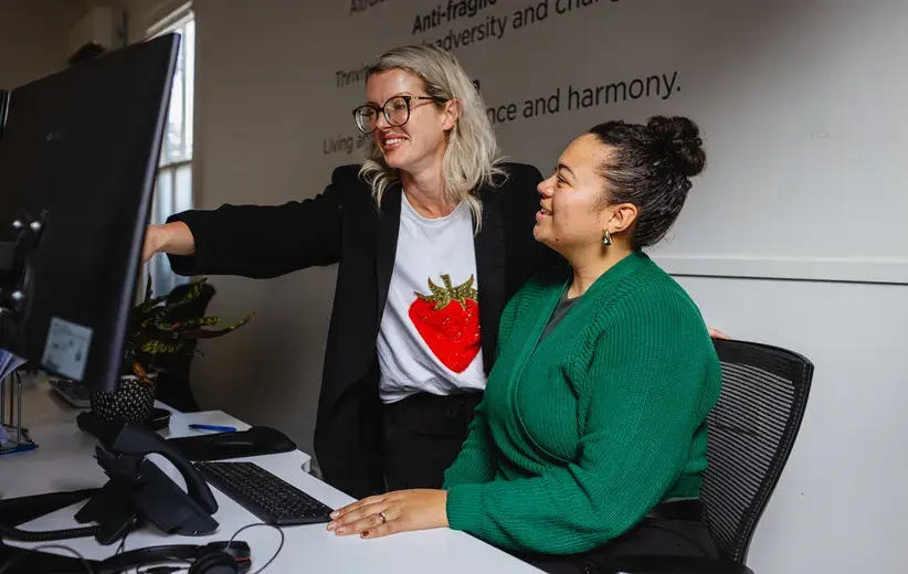 Two women working together at a computer, representing Now Reach's real-time call centre performance reporting for supervisors