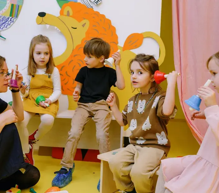 Group of young children playing with colorful bells in a daycare setting, representing Now NZ's partnership with the Early Childhood Council to support childcare centers with telco solutions.